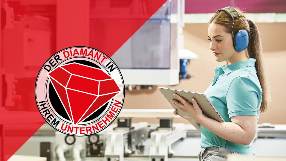 Eine Frau mit Gehörschutz bedient ein Tablet in einer Werkstatt. Links ein rotes Logo mit Diamant und Text „DER DIAMANT IN IHREM UNTERNEHMEN“.